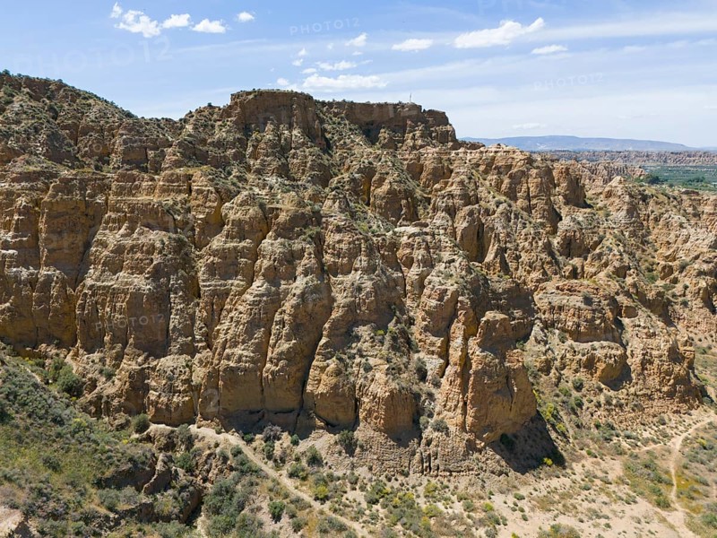 A rocky and hilly area with cliffs under a clear blue sky, aerial view, limestone tuff and loess rock, cave district, Troglodytos, Guadix, Granada, Andalusia, Spain, Europe