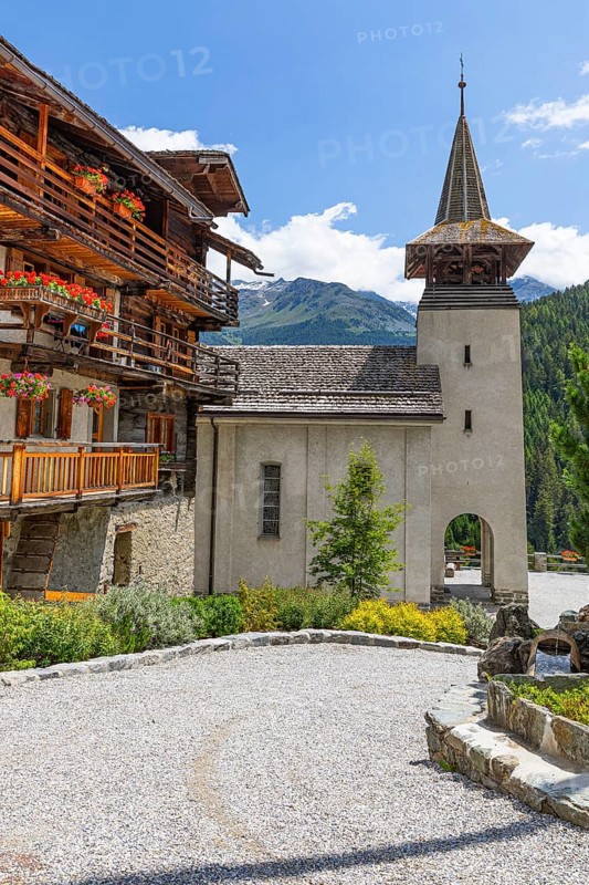 Old wooden house with flower boxes on balconies, Saint Theodule church behind, historic village centre, Grimentz, Val d'Anniviers, Valais Alps, Canton Valais, Switzerland, Europe
