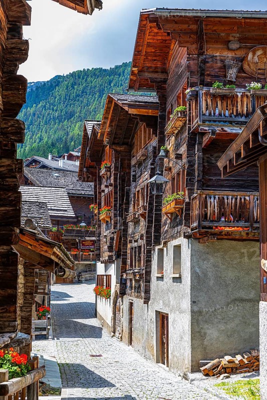 Paved footpath surrounded by old wooden houses, flower boxes on balconies and windows, historic village centre, Grimentz, Val d'Anniviers, Valais Alps, Canton Valais, Switzerland, Europe