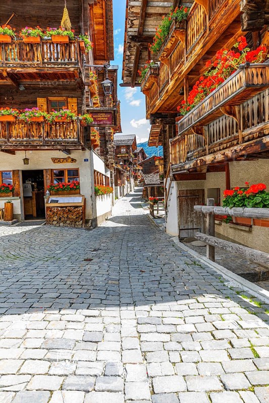 Paved footpath surrounded by old wooden houses, flower boxes on balconies and windows, historic village centre, Grimentz, Val d'Anniviers, Valais Alps, Canton Valais, Switzerland, Europe