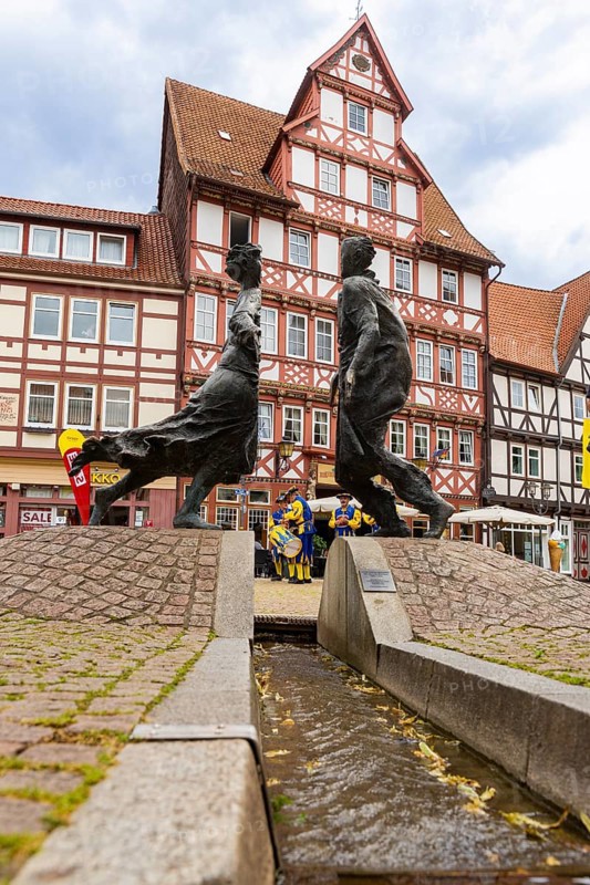 Duderstadt is a town and independent municipality in the district of Göttingen in south-east Lower Saxony. The predominantly medieval townscape is characterised by around 600 town houses of various styles - mainly half-timbered houses The town piper advertises the shooting festival. Reunification fountain Karl Henning Seemann 1996, Marktstrasse and historic Hotel zur Tanne, Duderstadt, Duderstadt, Lower Saxony, Germany, Europe
