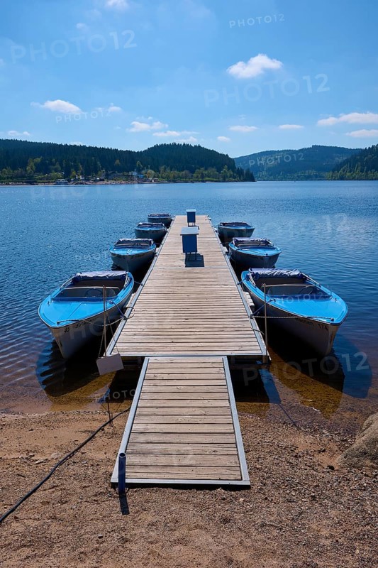 Jetty with moored boats on the Schluchsee, surrounded by mountains and forests, under blue sky, spring, Schluchsee, Black Forest, Baden-Württemberg, Germany, Europe