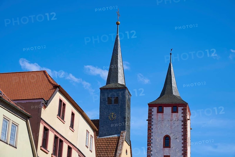 Two church towers and buildings in front of a blue sky in a cityscape, Karlstadt, Main Spessart, Bavaria, Germany, Europe
