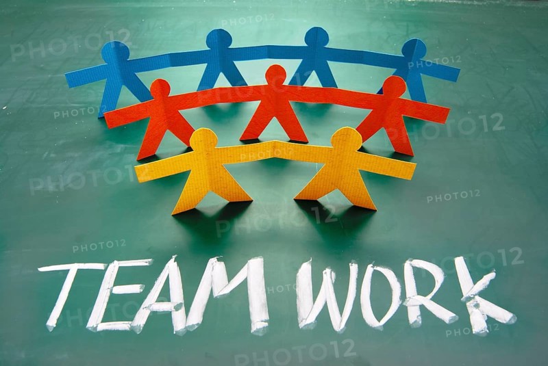 Teamwork words and colorful paper dolls on blackboard