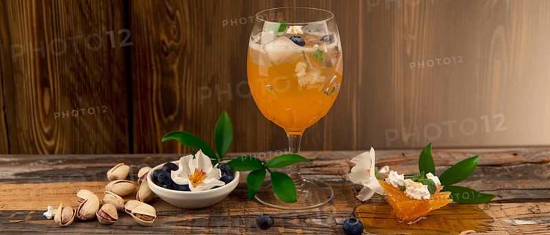 Refreshing cocktail with honeycomb, flowers, blueberries, and pistachios on rustic wooden table, AI generated
