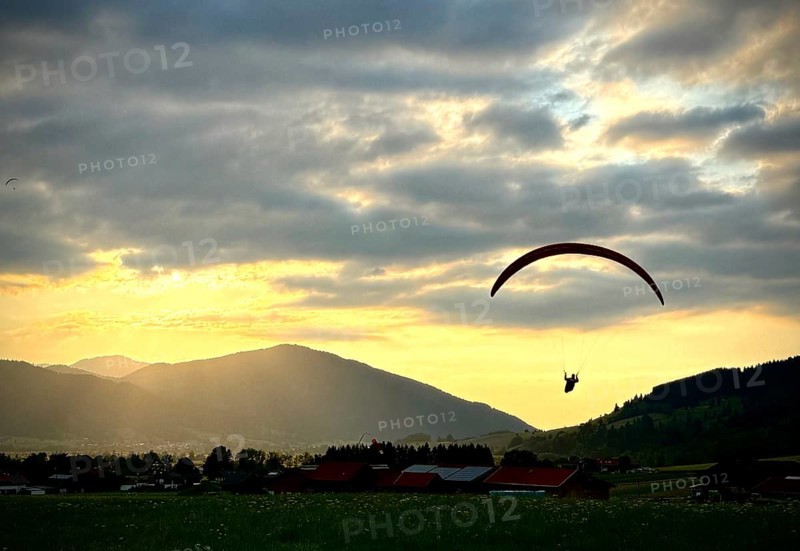 Paraglider lands in the sunset at the landing site Oberammergau, Bavaria, Germany, Europe