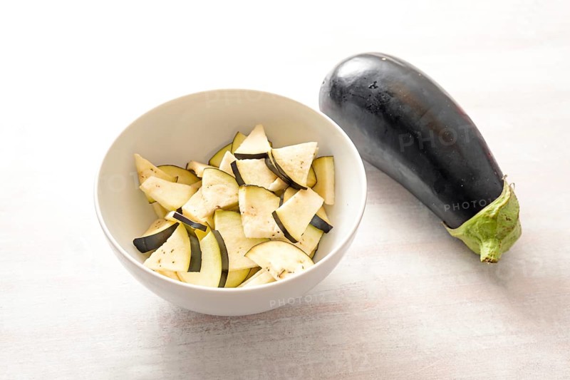 Eggplant, whole and chopped in a bowl, ingredient for various vegetable dishes, healthy vegetarian cooking concept, copy space, selected focus, narrow depth of field