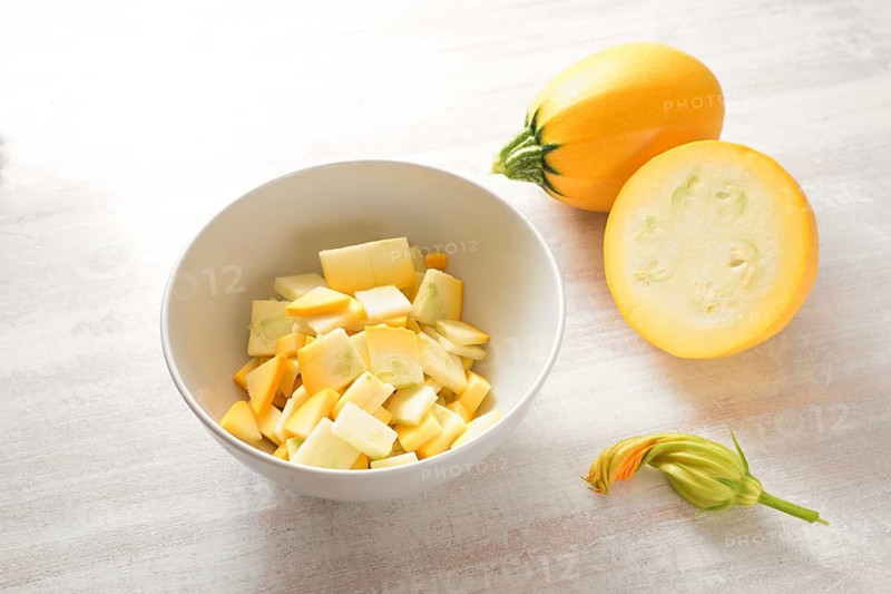 Yellow ball zucchini, whole, chopped in a bowl and an edible flower, ingredient for various vegetable dishes, vegetarian cooking concept, copy space, selected focus, narrow depth of field