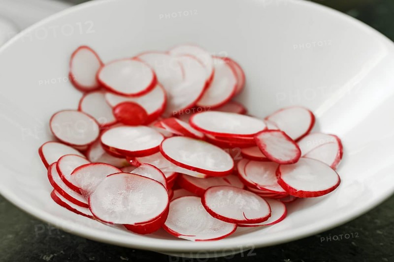 Slices of fresh raw radish in a white bowl, copy space, selected focus, narrow depth of field