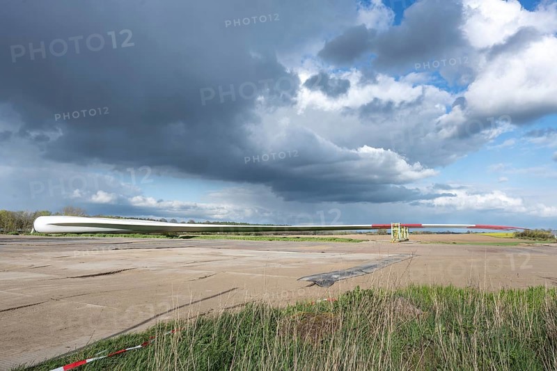 Blade of a wind turbine parked near the planned installation site, preparation for the construction of a renewable energy power plant, stormy clouds on the blue sky, copy space, selected focus