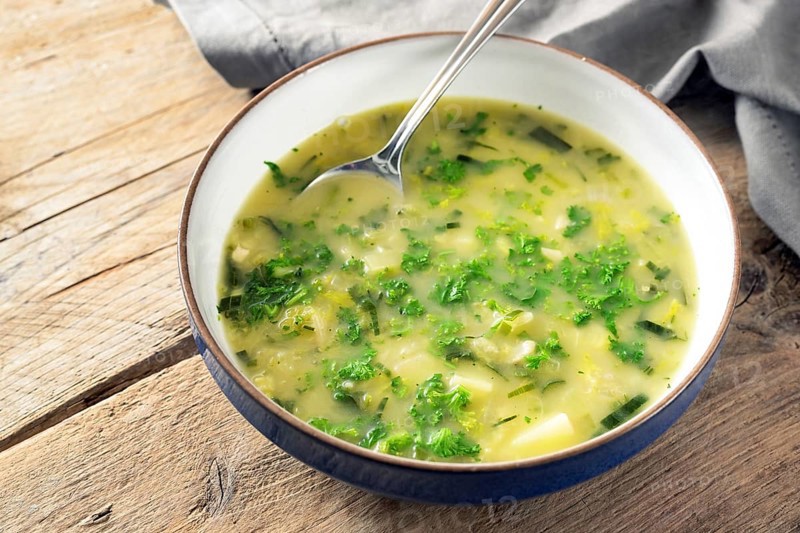 Potato parsley soup in a plate with spoon on a rustic wooden table, healthy vegetarian dish, copy space, selected focus, narrow depth of field
