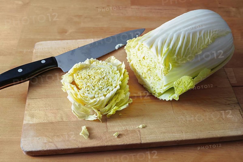 Cut slice of raw Chinese or napa cabbage on a wooden board and a kitchen knife, vegetarian cooking with vegetables, copy space, selected focus, narrow depth of field