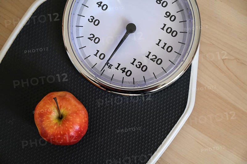 Red apple on an analogue personal scale on a wooden floor, concept for healthy eating, lose weight diet and fitness, high angle view from above, copy space