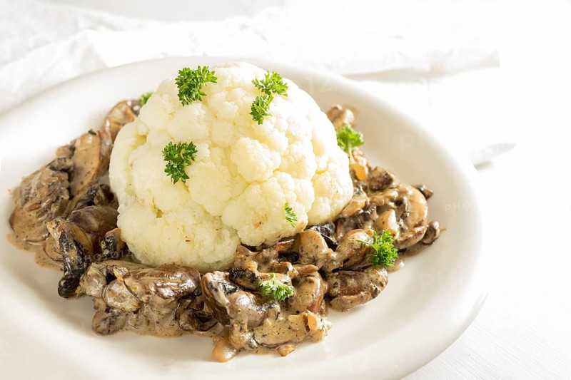 Cauliflower with mushroom ragout and parsley garnish, healthy vegetarian dish cooked from vegetables, copy space, selected focus, narrow depth of field