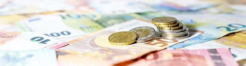 Stack of coins on euro banknotes as wide panoramic format, website header concept for business, finance or inflation, copy space, selected focus, narrow depth of field