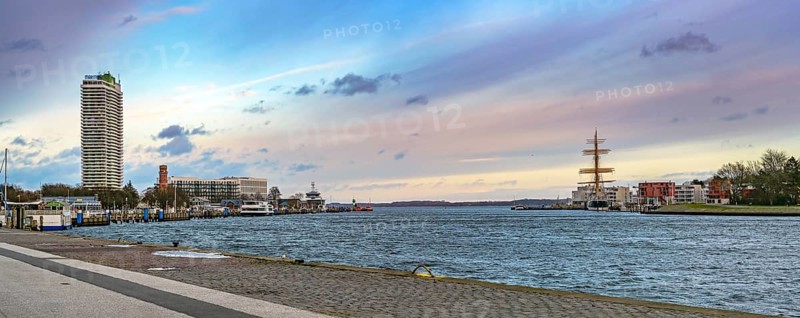 Lubeck Travemunde, Germany, January 15, 2023: Panorama with exciting sky, opening of the river Trave into the Baltic Sea between skyscraper hotel Maritim and sailing ship Passat, copy space, Europe
