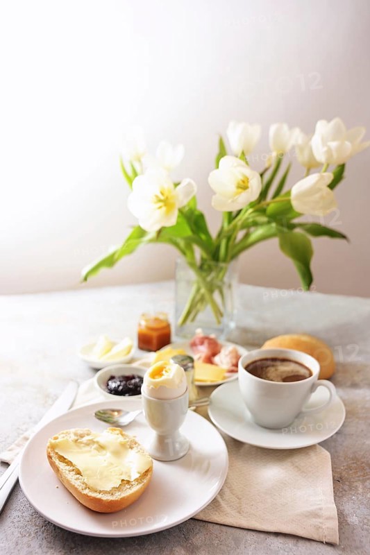 Breakfast table with flowers, bun, cooked egg, coffee and more, served with love at Sunday, birthday, valentines ore mothers day, light background, copy space, selected focus, narrow depth of field