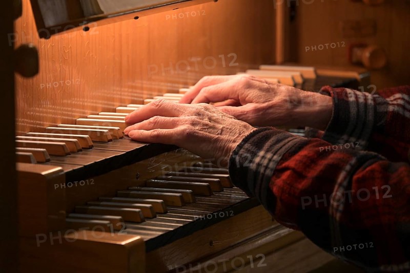 Old Hands of an organist playing on the organ keyboard also called manual, traditional musical instrument in the church, copy space, selected focus, narrow depth of field