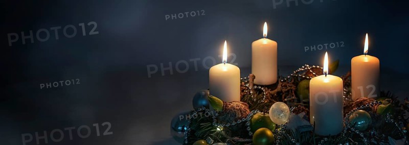 Lights in the night, four white Advent candles on a wreath with Christmas decoration against a dark blue background, panoramic format, copy space, selected focus, narrow depth of field
