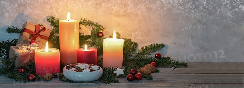 Advent candles in warm colors, cinnamon stars, Christmas decoration and fir branches on a rustic wooden table, panoramic format, copy space, selected focus, narrow depth of field