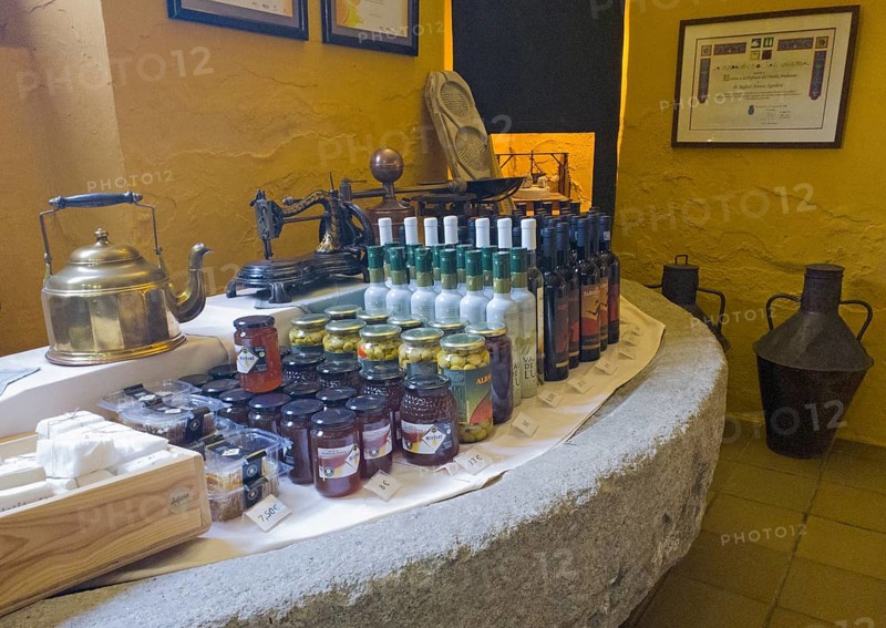 Display of products on a stone table surrounded by a yellow wall, including bottles and jars, products from the Tabernas desert, olives, olive oil, desert, Almeria, Andalusia, Spain, Europe