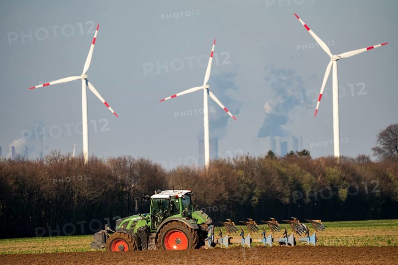 Tractor ploughing a field in spring, wind turbines, behind the Neurath brewery coal-fired power station, Rhenish lignite mining area