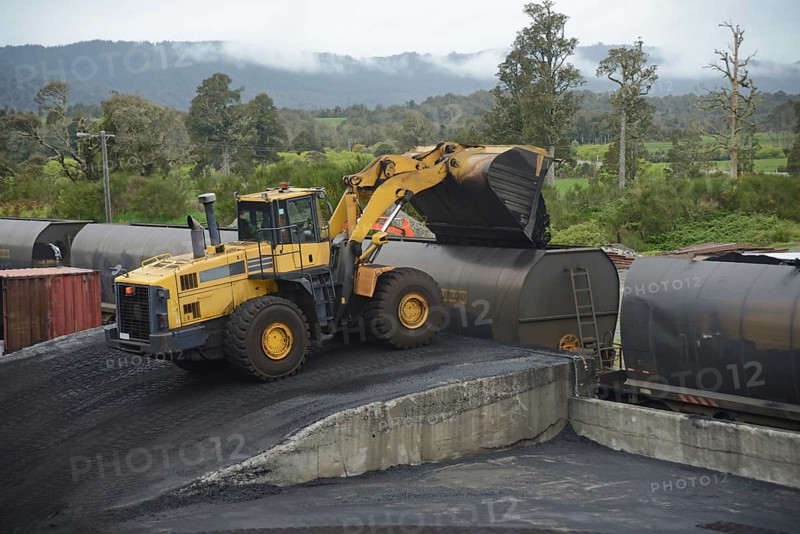 A payloader fills train wagons with coal at a railway siding