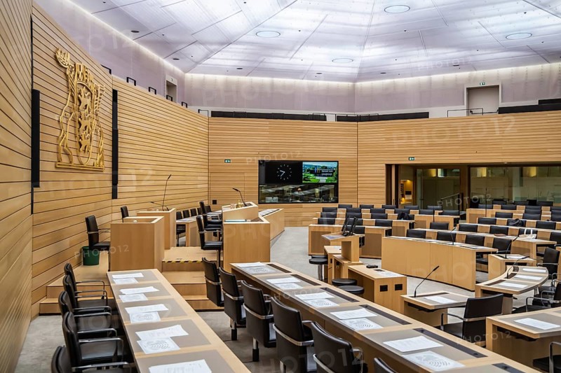 State parliament of Baden-Württemberg, assembly hall with state coat of arms. The seats of the members of parliament and ministers are empty. Stuttgart, Baden-Württemberg, Germany, Europe