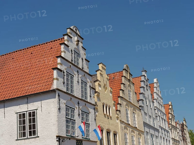Historic houses with Dutch flags and distinctive gables under a blue sky, friedrichstadt, schleswig-holstein, germany