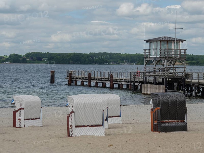 Three beach chairs on a sandy beach, in the background a wooden jetty and the sea under a cloudy sky, Glücksburg, Schleswig-Holstein, Germany, Europe