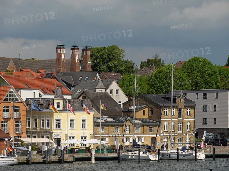 Town view with historic buildings, chimneys and boats on the waterfront under a cloudy sky, Kappeln, Schleswig-Holstein, Germany, Europe