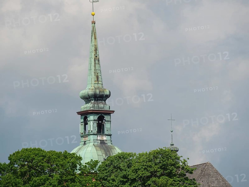 Detail of a church tower in front of a cloudy sky with green trees in the foreground, Kappeln, Schleswig-Holstein, Germany, Europe