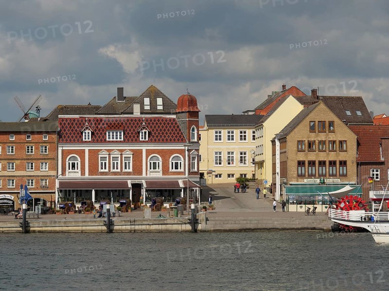 Historic buildings and tourists along a harbour shore under a cloudy sky, Kappeln, Schleswig-Holstein, Germany, Europe