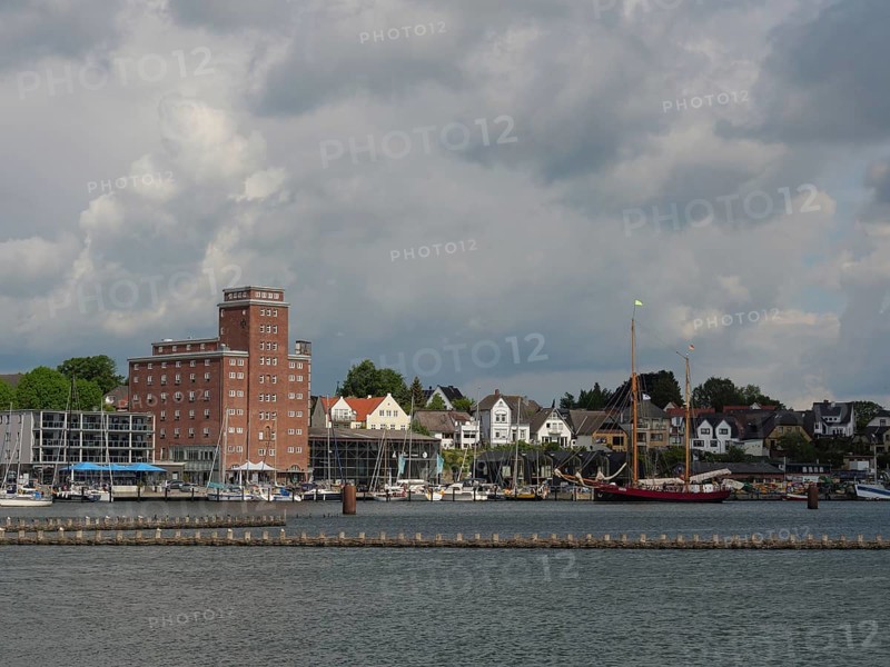 Buildings and boats along a coastline under a cloudy sky, Kappeln, Schleswig-Holstein, Germany, Europe