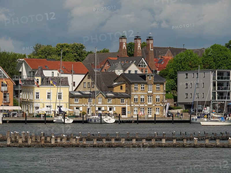 Coastal town with many buildings and boats on the water, under a partly cloudy sky, Kappeln, Schleswig-Holstein, Germany, Europe