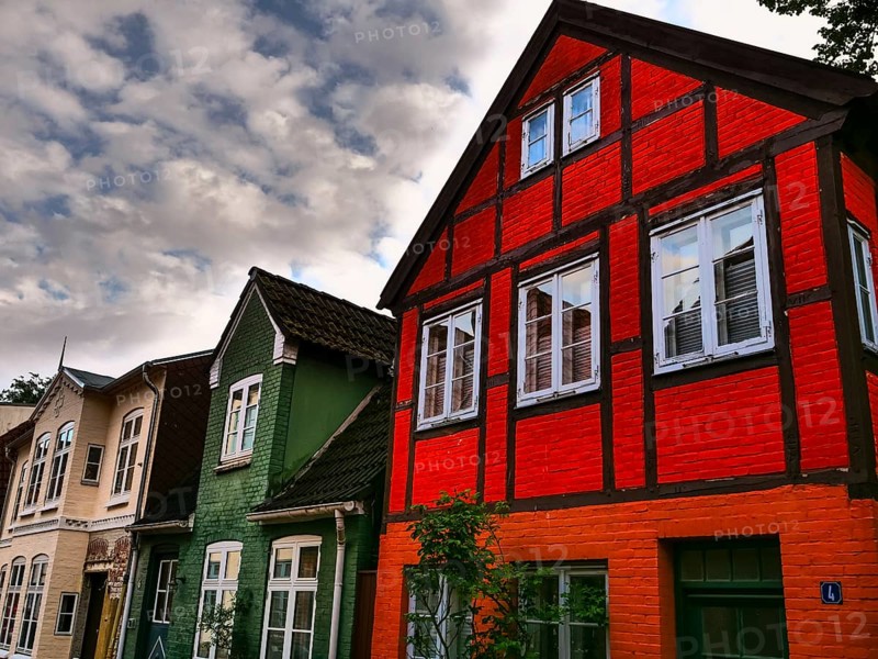 Cornice decorated half-timbered houses in red and green under a cloudy sky, Eckernförde, Schleswig-Holstein, Germany, Europe