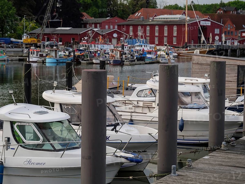 Some boats are moored at a wooden jetty in a harbour, red buildings in the background, Eckernförde, Schleswig-Holstein, Germany, Europe