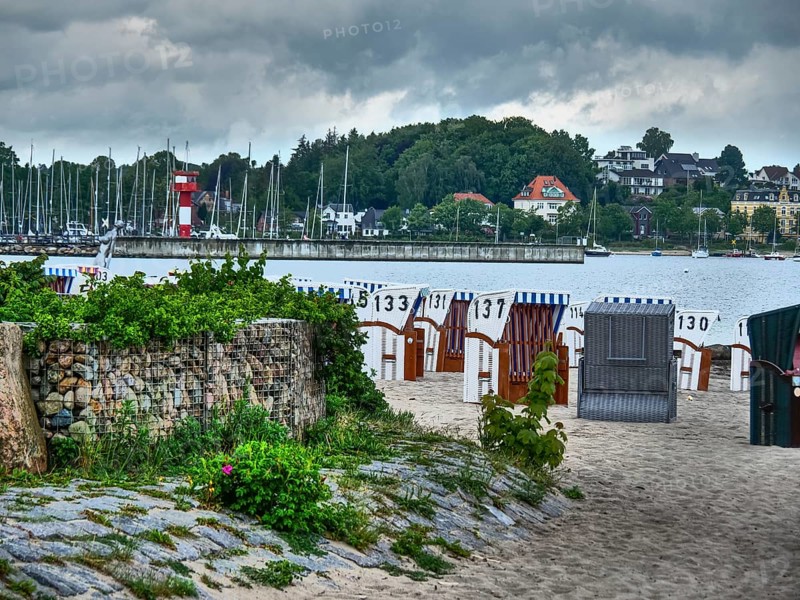 Beach with numbered beach chairs, boats in the water and a lighthouse in the background, Eckernförde, SChleswig-Holstein, Germany, Europe