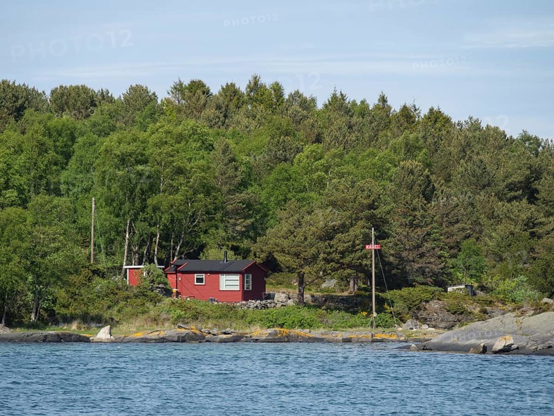 A red house on the edge of the forest near the coast, surrounded by trees and water, Stavanger, Norway, Europe