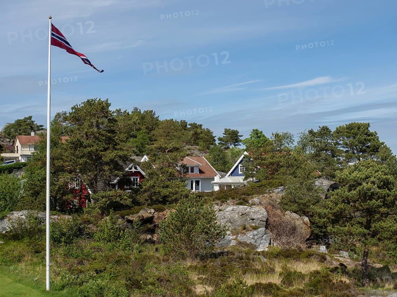 Norwegian landscape with green houses, flagstaff and wooded hills under blue sky, Stavanger, Norway, Europe