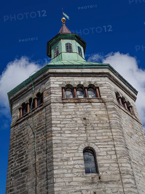 Historic stone tower with striking clock and flag. Bright blue sky in the background, Stavanger, Norway, Europe