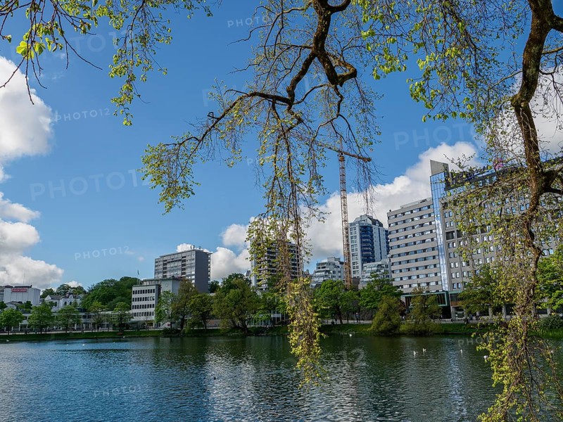 Urban building backdrop by a lake, surrounded by trees and blue sky with clouds, Stavanger, Norway, Europe