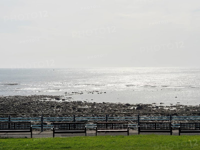 Panoramic view of the sea with benches in the foreground and shiny water surface, Newcastle, England, Great Britain