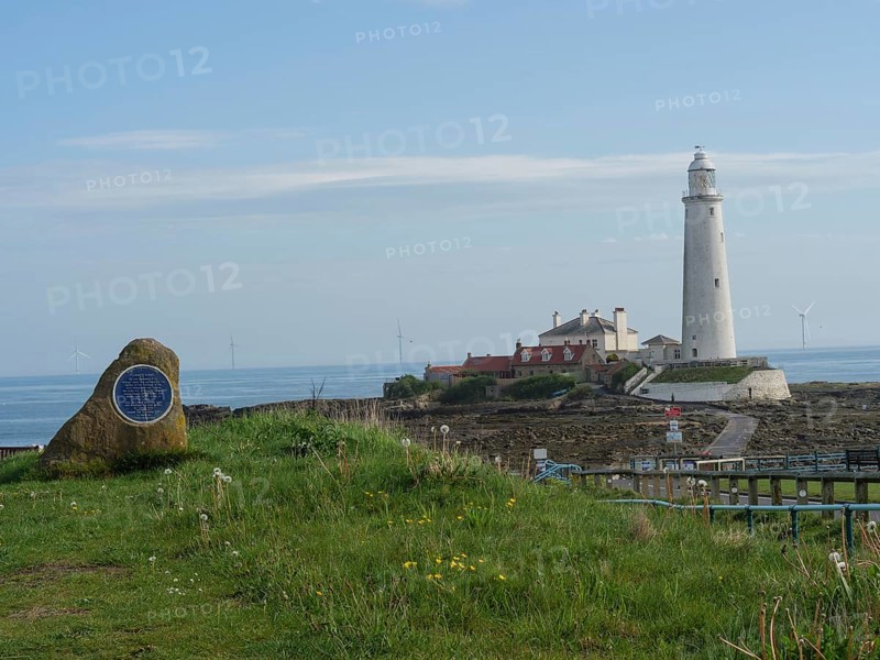 A coastal landscape with a lighthouse in the background and a stone with a plaque in the foreground, Tynemouth, England, Great Britain