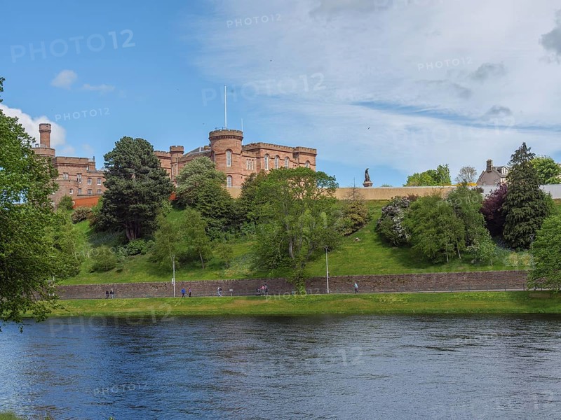 View of a castle on a hill, below a calm river with green banks and a spring-like sky, inverness, Scotland, United Kingdom, Europe