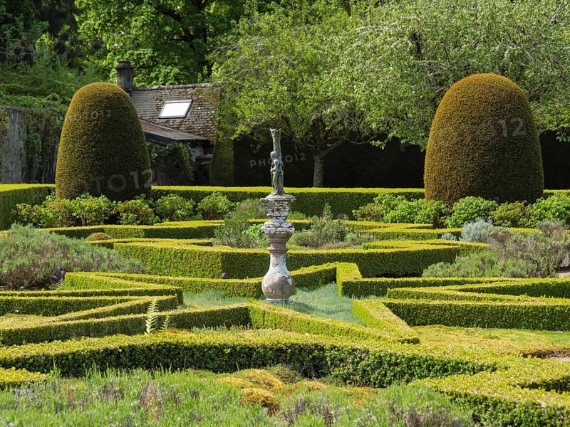 A formal garden with symmetrically trimmed hedges and a central sculpture, all set in a verdant landscape, inverness, Scotland, United Kingdom, Europe