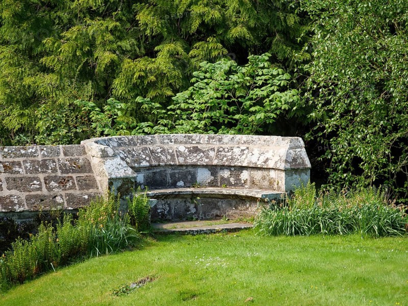 An old stone bench in a historic garden surrounded by green trees and plants, inverness, Scotland, United Kingdom, Europe