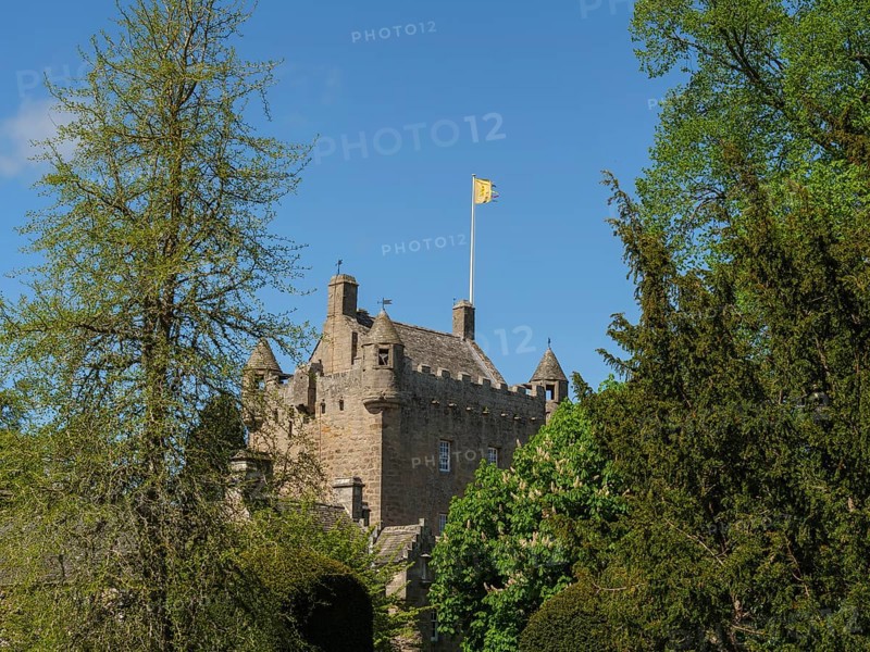A historic castle with a waving flag on the tower, surrounded by green trees, inverness, Scotland, Great Britain