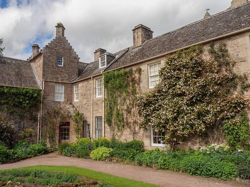 Stone house with climbing plants and windows, surrounded by flowers and garden, inverness, Scotland, Great Britain