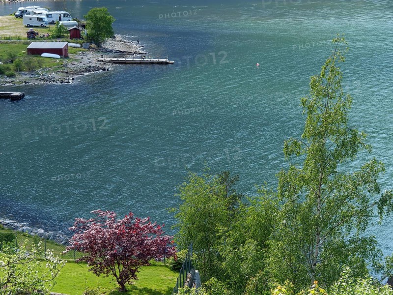 A lake with calm blue water, trees along the shore and some camping and boating facilities in the background, Eidfjord NOR 3